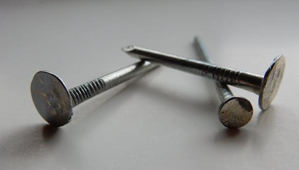 Detailed image of three metallic nails on a white background, highlighting texture and shape.